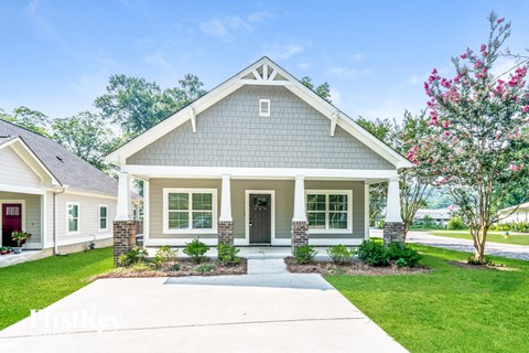 a white and green house with a sidewalk in front of it