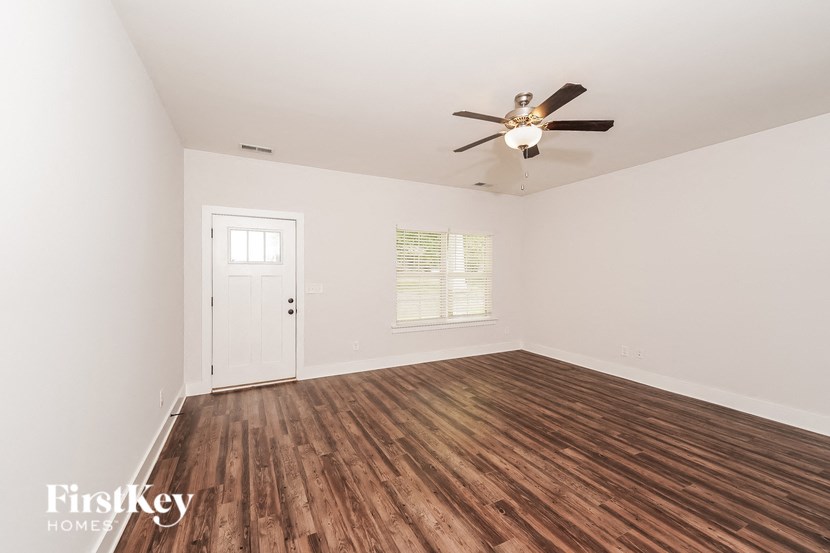 the living room of a home with wood flooring and a ceiling fan