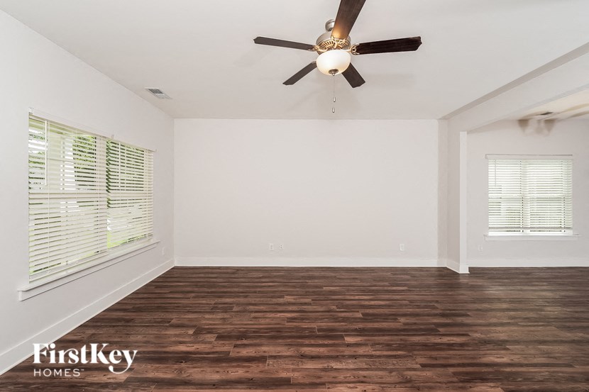 an empty living room with a ceiling fan and a window
