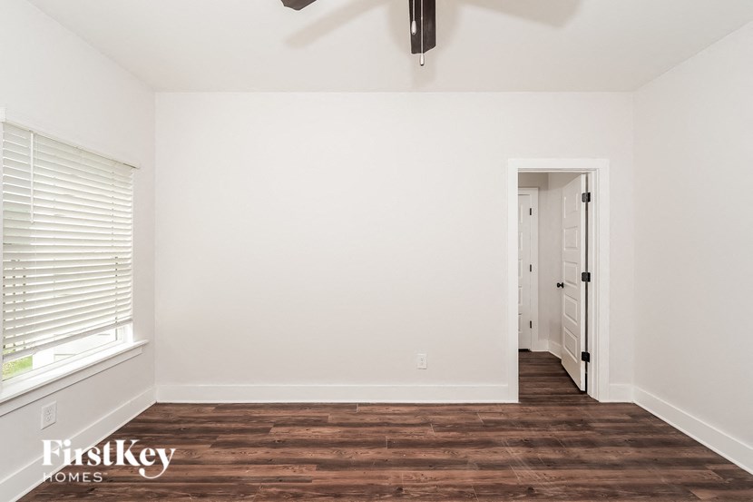 a bedroom with white walls and wood flooring and a ceiling fan
