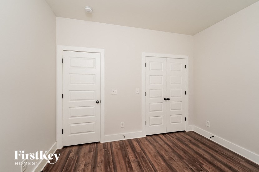 the living room of a home with white doors and wood floors