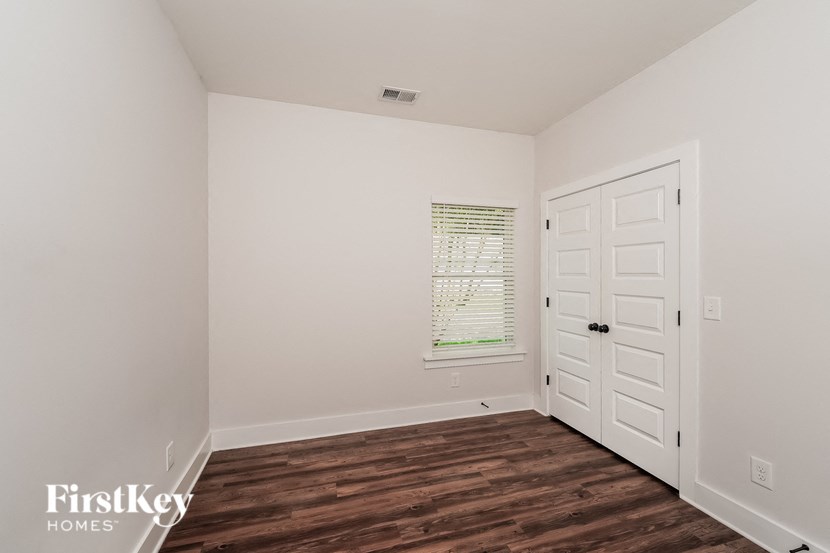 a bedroom with white walls and a white door and wood floors