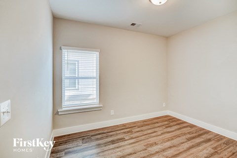 a bedroom with a wood floor and white walls and a window