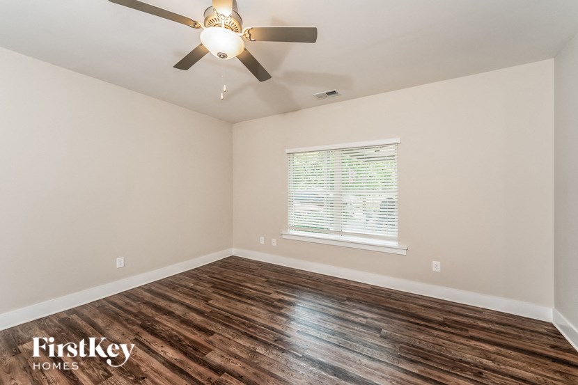 the spacious living room with hardwood flooring and a ceiling fan