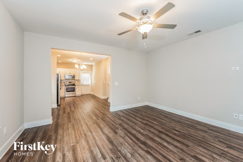 an empty living room with a ceiling fan and a kitchen