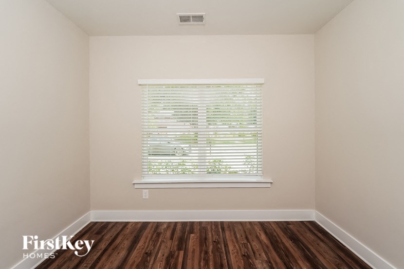 a bedroom with wood floors and a window