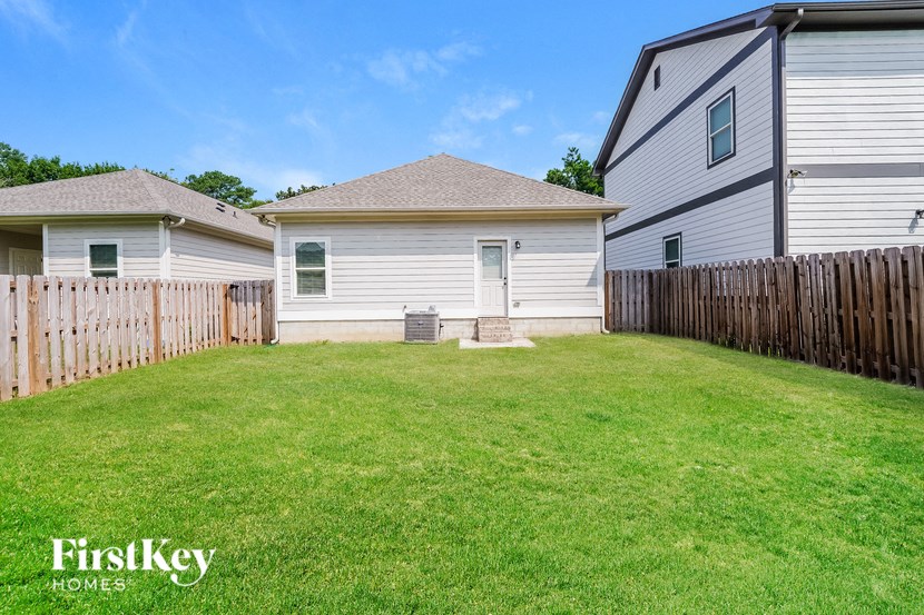 a backyard with a white house and a wooden fence