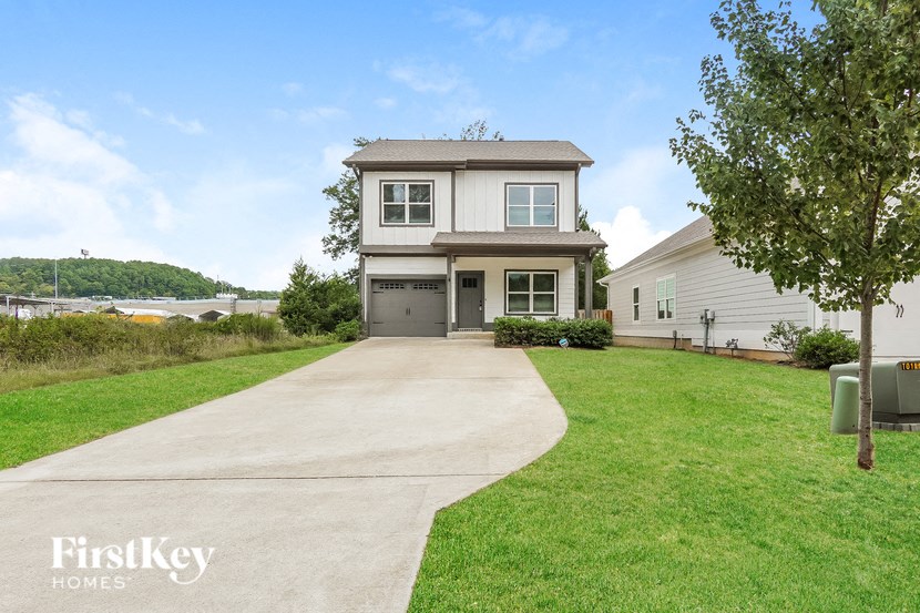 a house with a driveway and a lake in the background