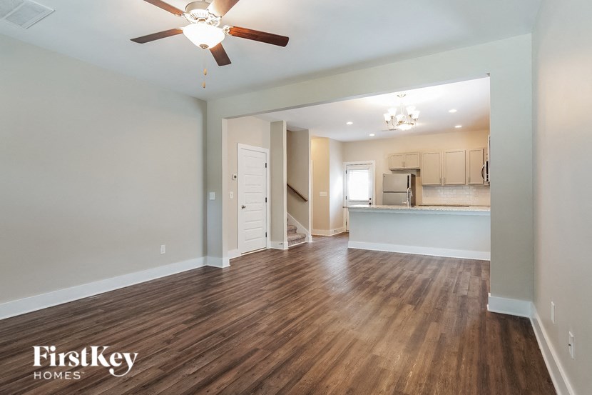 an empty living room with a ceiling fan and a kitchen