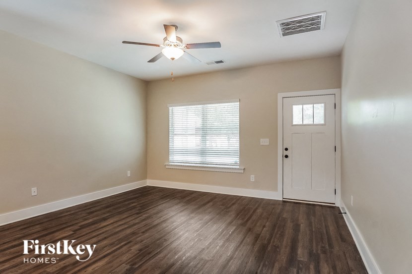 an empty living room with a ceiling fan and a door