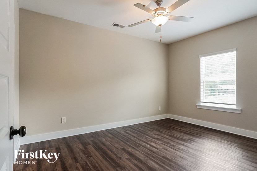 an empty room with wood flooring and a ceiling fan