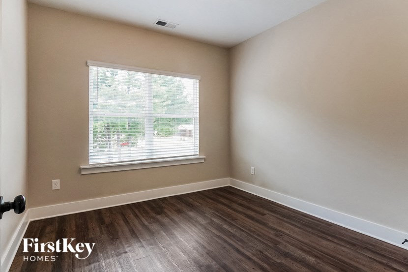 the living room of a home with a large window and wooden floors