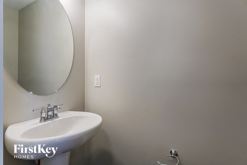 a bathroom with a white sink and a oval mirror