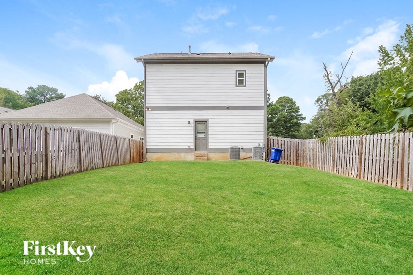 a small white house with a yard and a fence