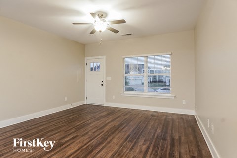 an empty living room with a ceiling fan and a window