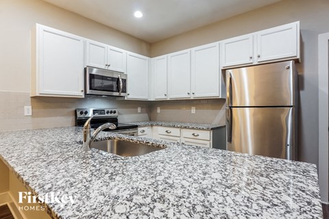 a kitchen with a granite counter top and stainless steel refrigerator