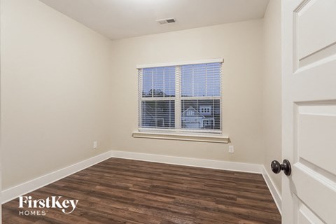 a bedroom with a window and wood floors