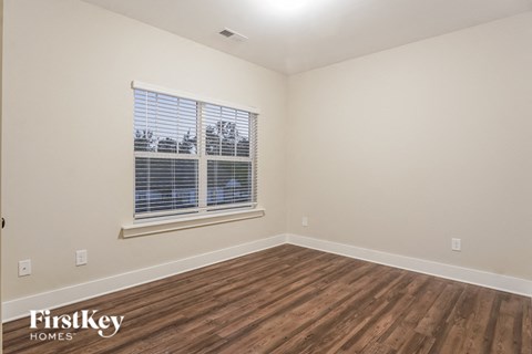 the living room of a home with wood flooring and a window