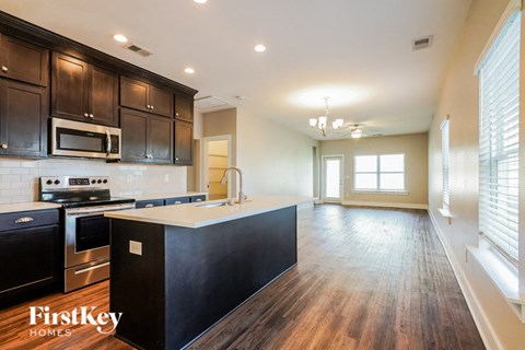 A kitchen with dark wood cabinets and a black island.