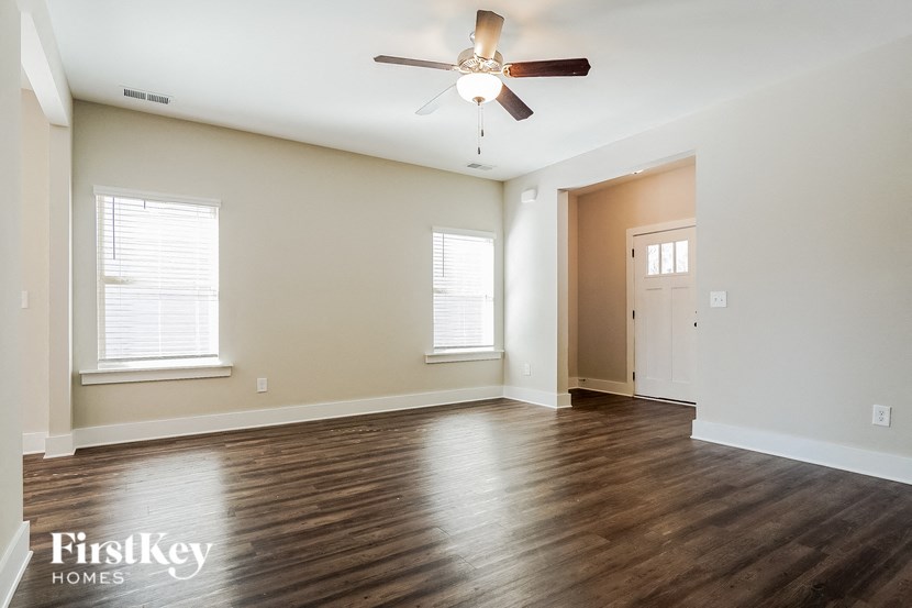 an empty living room with wood floors and a ceiling fan