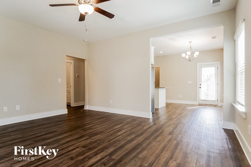 the living room and dining room of an empty house with a ceiling fan