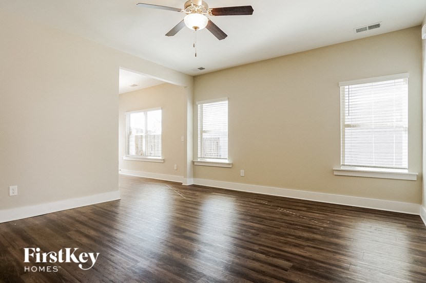 the spacious living room with hardwood floors and a ceiling fan