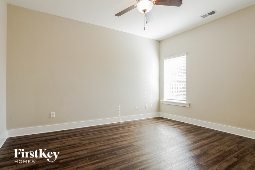 the spacious living room with wood flooring and a ceiling fan