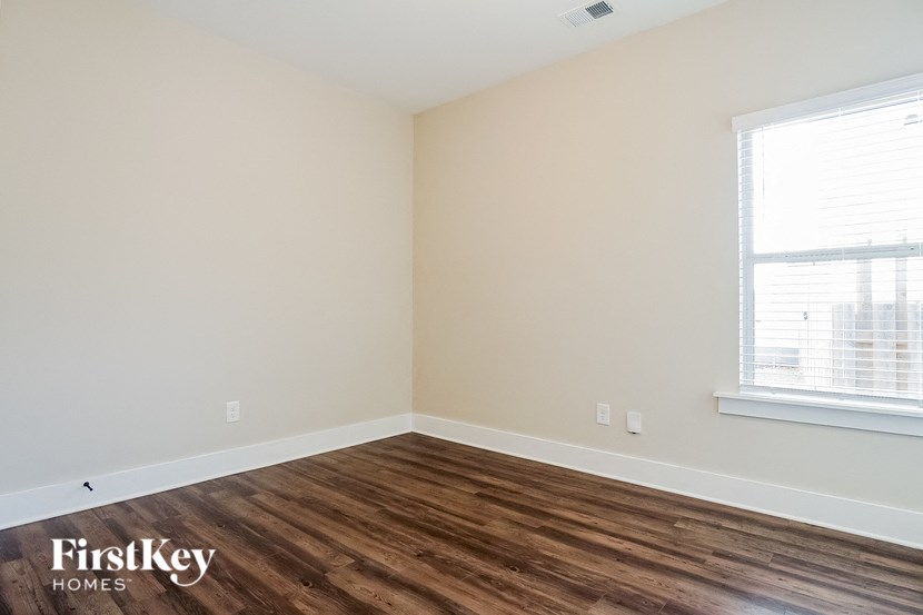a bedroom with wood floors and white walls and a window