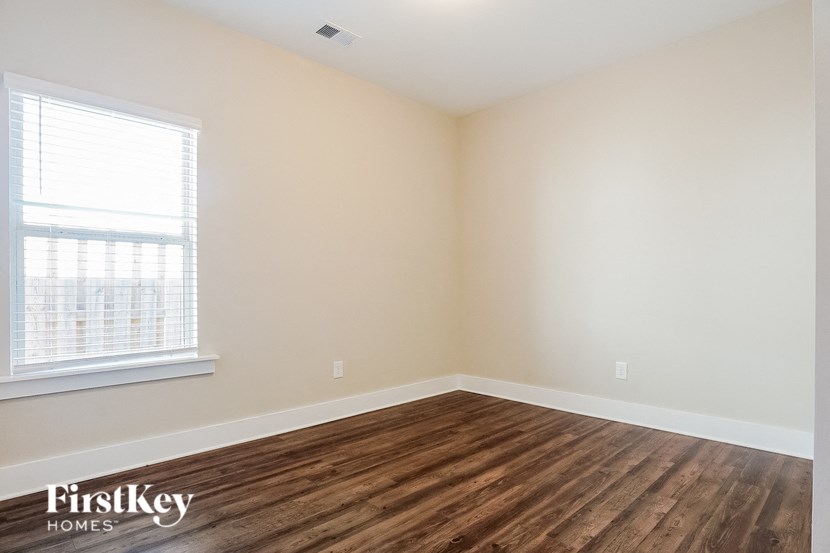 the living room of a home with wood flooring and a window