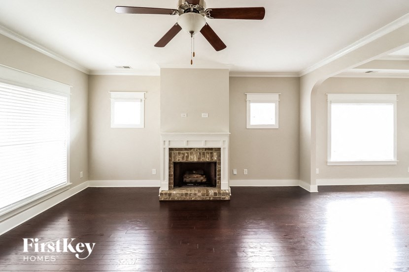 a living room with a fireplace and a ceiling fan