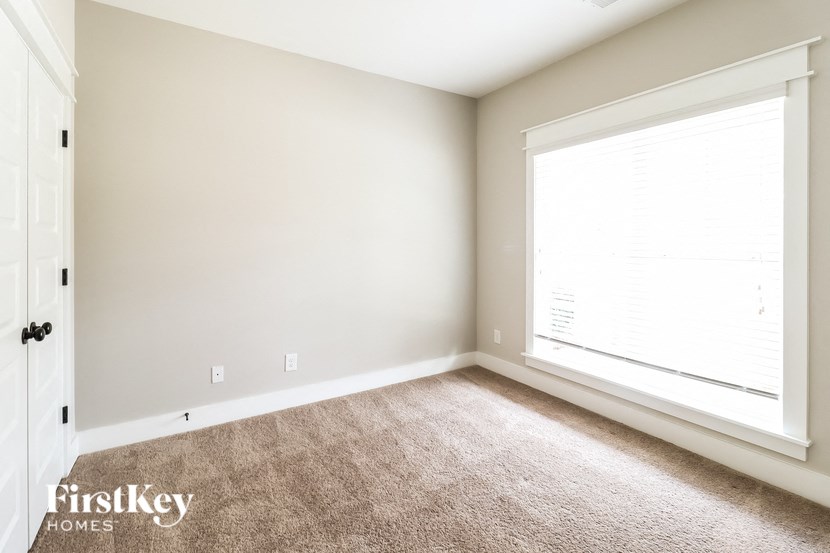 an empty room with a large window and carpet
