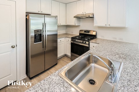 A kitchen with a stainless steel refrigerator, stove, and sink.