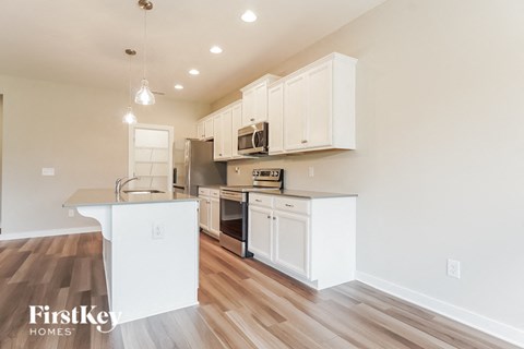 A kitchen with white cabinets and a wooden floor.