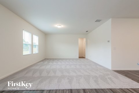 A spacious room with a rug on the floor and a door on the right side.