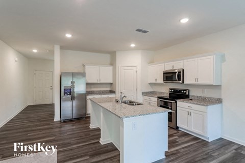A kitchen with white cabinets and a wooden floor.