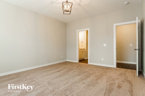 a spacious living room with carpet and a door to the bathroom
