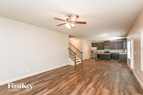 an open living room with a kitchen and a ceiling fan