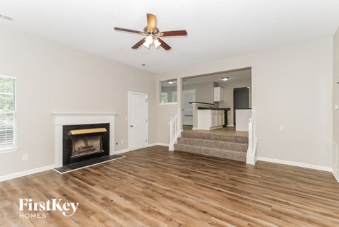 A spacious living room with wood flooring and a fireplace.