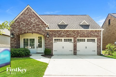 a brick house with white garage doors and a lawn