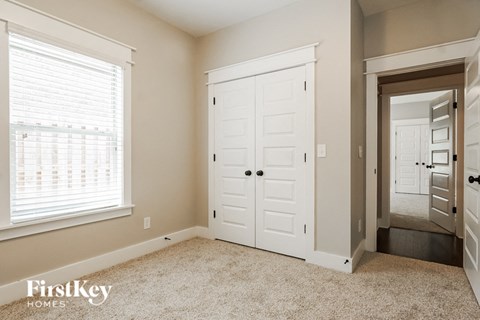 a bedroom with a closet and a white door and a window