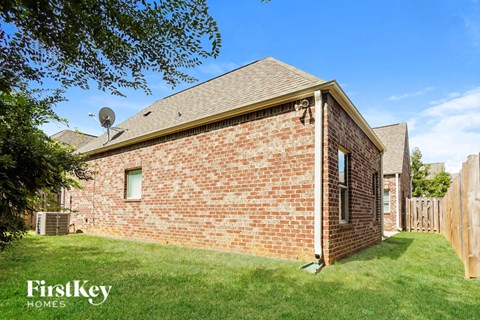 the view of the back of a brick house with a yard and grass