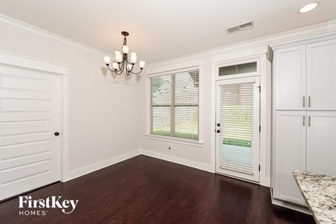 a dining room with white cabinets and a large window and a door to a kitchen