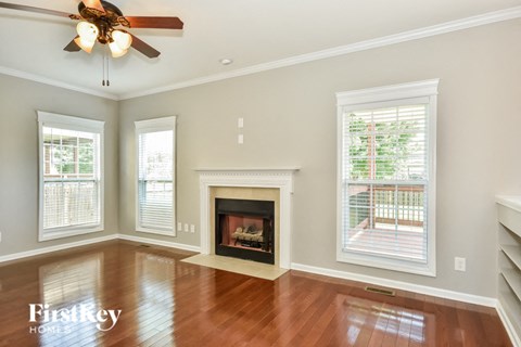 A spacious living room with a fireplace and a ceiling fan.