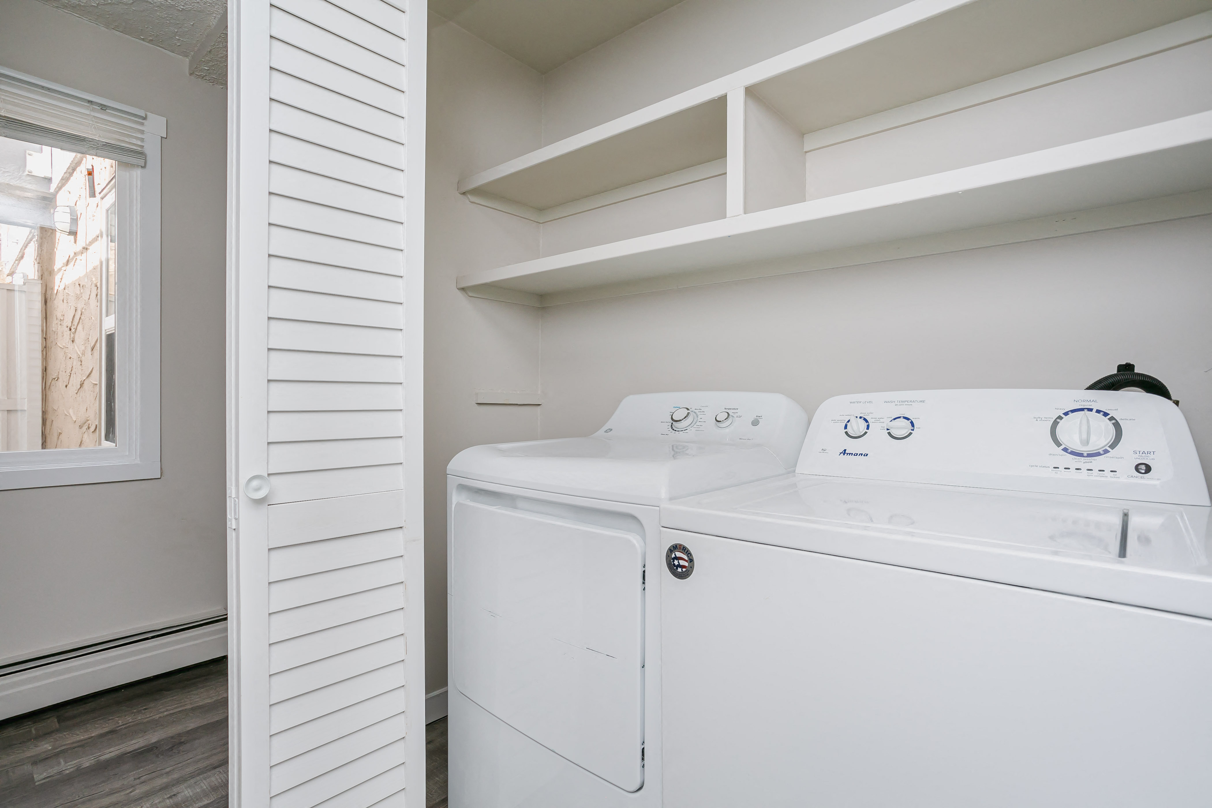 a washer and dryer in a laundry room with white walls and a window