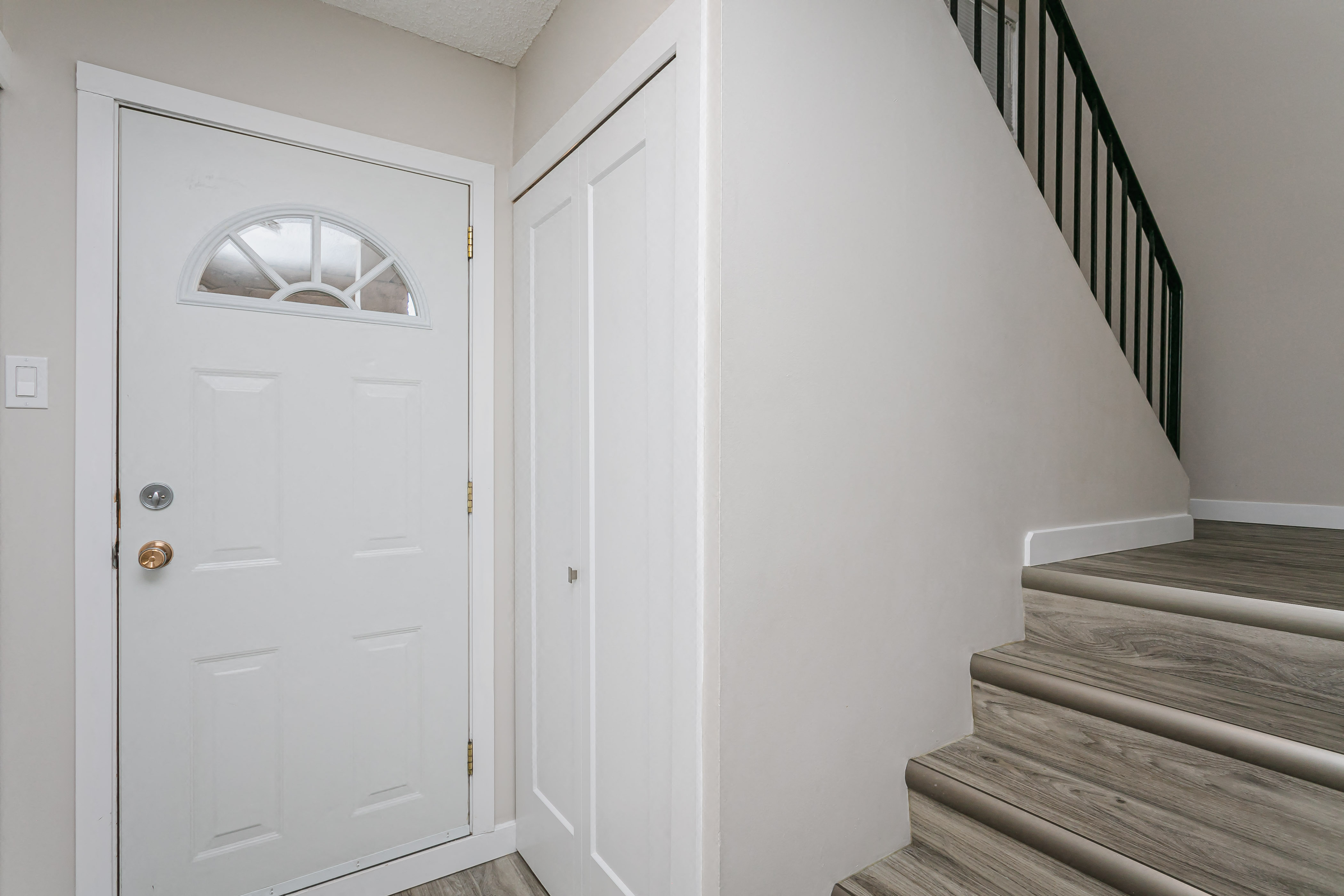 a white door and stairs in a home with white walls