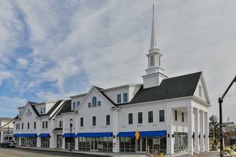 a white church with a steeple on the corner of a street
