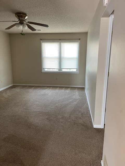 an empty room with a ceiling fan and a window