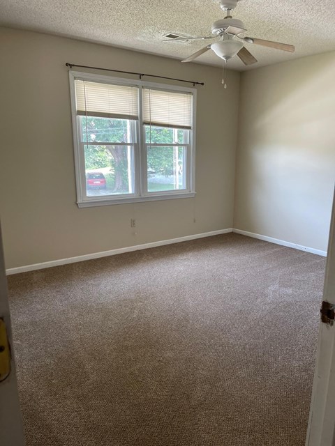 an empty room with a ceiling fan and two windows