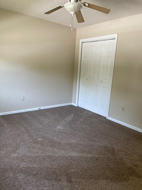 a room with a carpeted floor and a ceiling fan