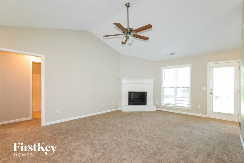 A spacious living room with a fireplace and a ceiling fan.